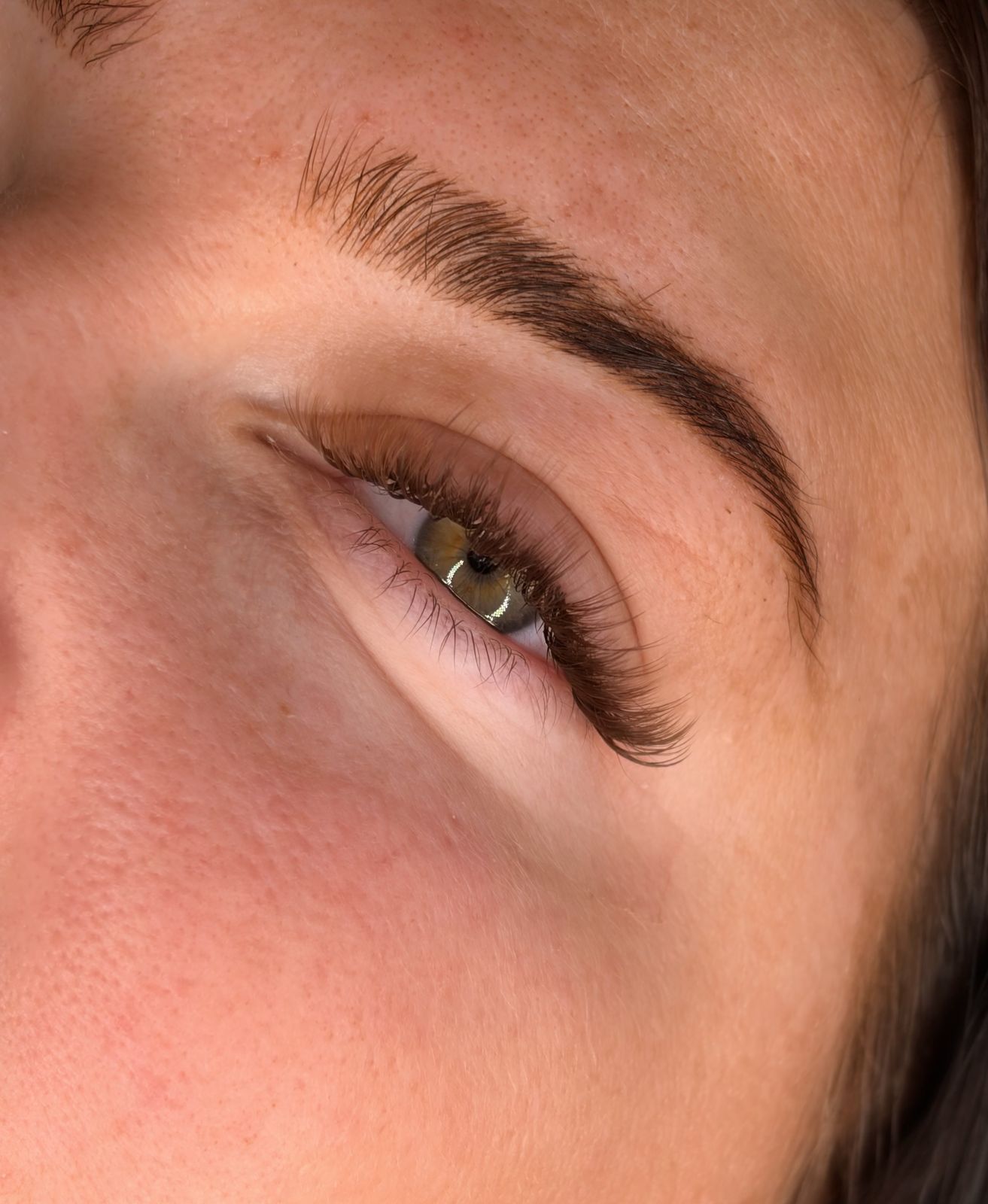 Soft natural lash look with a groomed brow, close up
